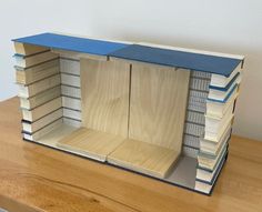 an open book case sitting on top of a wooden table next to a pile of books