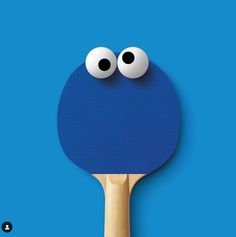 a ping pong paddle with two eyes on it's side, against a blue background