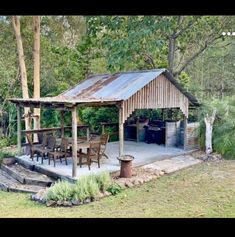 an outdoor kitchen and dining area in the woods