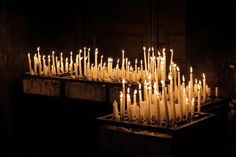 many lit candles are placed in a dark room