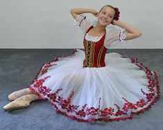 a woman in a red and white dress sitting on the floor with her hands behind her head