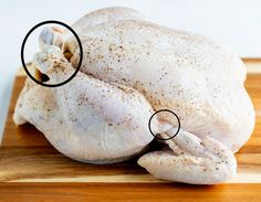 a whole chicken sitting on top of a wooden cutting board