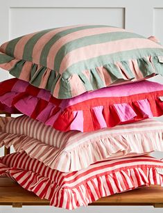 four pillows stacked on top of each other in different colors and patterns, all piled together