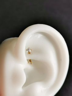 a pair of ear piercings sitting on top of a white plastic container with a black background