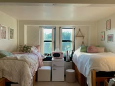 two beds in a room with windows and pictures on the wall next to each other