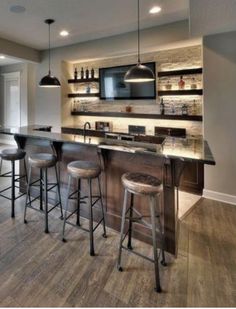 a kitchen with an island and bar stools next to the counter top in front of it