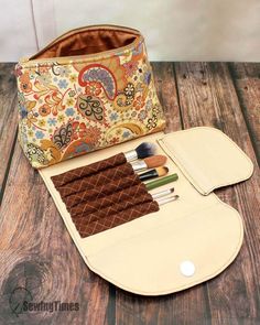 an open purse sitting on top of a wooden table next to a brush and makeup bag