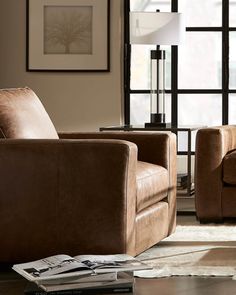 a living room with two brown chairs and a lamp