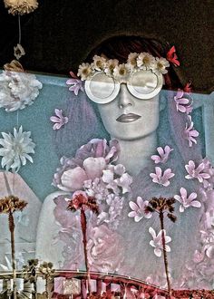 a woman with flowers in her hair and glasses on top of a large painting that looks like she is surrounded by palm trees