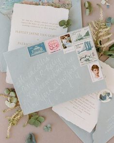 an assortment of envelopes and postcards on a table with flowers, leaves and other items