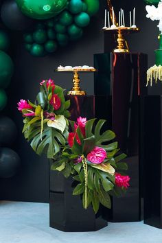 three black vases with flowers in them on a table next to balloons and decorations