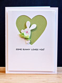 some bunny loves you card with a green heart and white rabbit in the center, on a wooden table