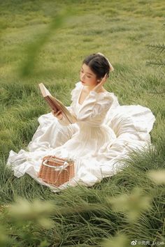 a woman sitting in the grass reading a book