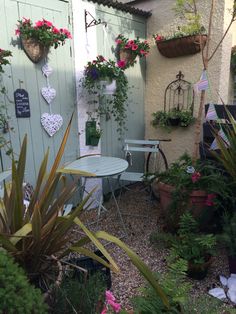 an outdoor patio area with potted plants and flowers on the wall, next to a small table