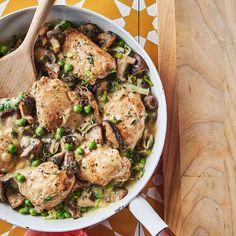 a skillet filled with chicken, mushrooms and peas