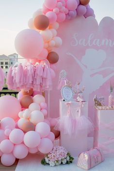 a pink and white ballerina themed birthday party with balloons, streamers, tissue pom poms