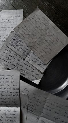 several pieces of paper on top of a table with papers scattered about it and one piece of black plate in the middle