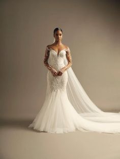 a woman in a wedding dress posing for the camera with her veil draped over her shoulder