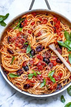 a skillet filled with spaghetti and olives