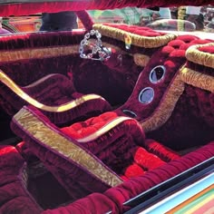 the interior of an old car with red velvet upholstered seats and gold trim