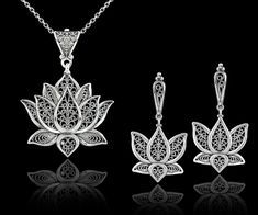 "This 925 sterling silver filigree art blossoming lotus flower pendant and dangle drop earrings set is a true work of art. The filigree silverwork is delicate and intricate, creating a beautiful open-air design that showcases the lotus flower in full bloom. The dangle drop style of the pendant and earrings adds a touch of movement to the overall design, making this set both stylish and eye-catching.       Whether you're dressing up for a special event or just want to add some beauty to your everyday look, this set is sure to make a statement. The sterling silver material also ensures that this set will last for years to come, making it a great investment piece for your jewelry collection. Earrings; The length of the earrings is 1.70\"  and the width is 0.90\". The total weight is 7.50 gr. Elegant Filigree Jewelry Sets, Sterling Silver Jewelry Sets With Intricate Design, Sterling Silver Jewelry Sets With Intricate Design For Gift, Fine Jewelry With Filigree Dangle, Fine Jewelry Dangle Earrings With Filigree, Delicate Pierced Flower-shaped Jewelry, Silver Filigree Jewelry Sets As Gift, Sterling Silver Dangle Jewelry With Intricate Design, Spiritual Sterling Silver Flower Shaped Jewelry