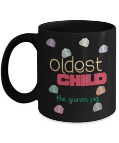 a black coffee mug with the words oldest child on it and colorful confetti