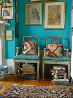 two chairs sitting next to each other on top of a hard wood floor covered in books