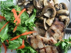 a white plate topped with meat and veggies next to a knife and fork