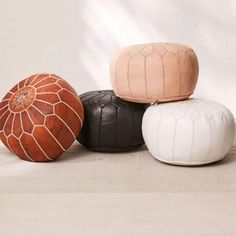 four different colored poufles sitting next to each other on the floor in front of a white wall