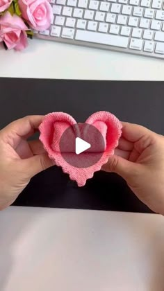 someone is holding a heart shaped object in front of a computer keyboard and pink roses