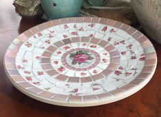 a white plate with pink flowers on it sitting on a table next to two vases