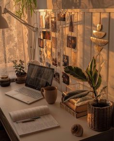 an open laptop computer sitting on top of a desk next to a potted plant