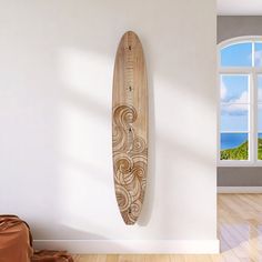 a wooden surfboard hanging on the wall next to a window with an ocean view