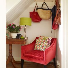 a red chair sitting next to a wooden table with a lamp on top of it