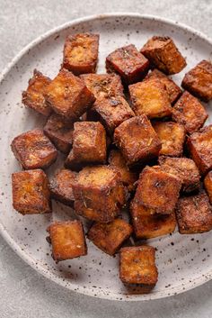 a white plate topped with tofu pieces on top of a table