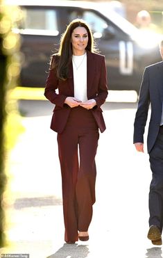 the woman is walking down the street with her hands in her pockets and wearing a suit