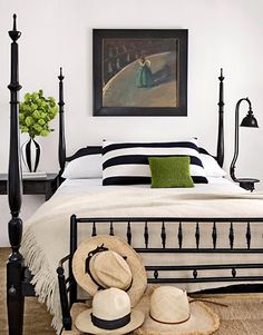 a bedroom with black and white bedding, green pillows and hats on the floor