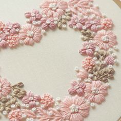 a close up of a piece of embroidery on a white cloth with pink flowers and pearls