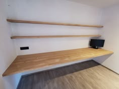 an empty room with two wooden shelves and a small tv on the shelf next to it