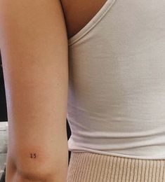 a woman with a small tattoo on her left arm and the number thirteen tattooed on her right arm