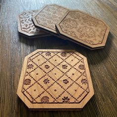 three wooden coasters sitting on top of a wooden table next to each other with intricate designs