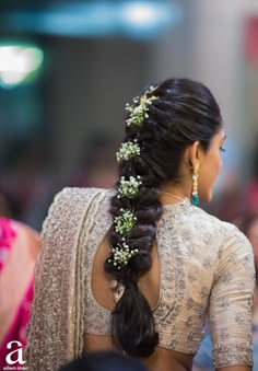 a woman with long hair wearing a white blouse and flowers in her hair, looking back