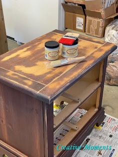 an old wooden table with paint and some boxes on the floor next to each other