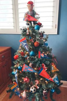 a small christmas tree decorated with ornaments and flags is in the corner of a room