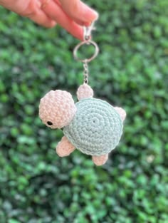 a hand holding a crocheted keychain shaped like a turtle