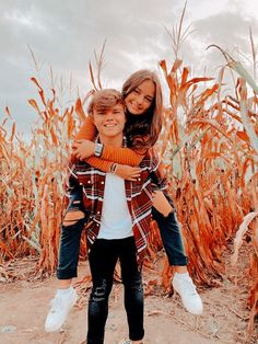 two children hugging each other in front of a corn field