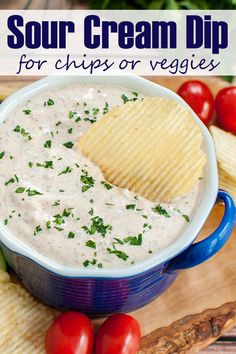 a blue bowl filled with dip and chips on top of a cutting board next to tomatoes