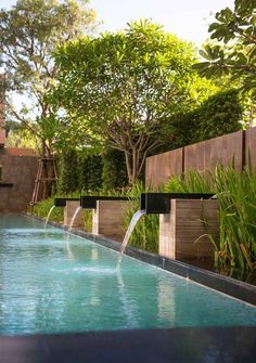 an outdoor swimming pool with water running from it's sides and trees in the background