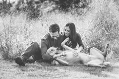 a man and woman petting a cow in a field with tall grass behind them