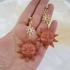 two sun and star earrings are shown in the palm of a person's hand